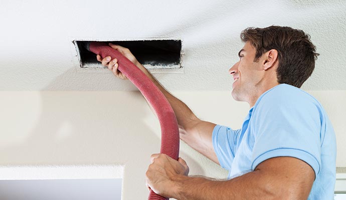 Professional worker cleaning air duct