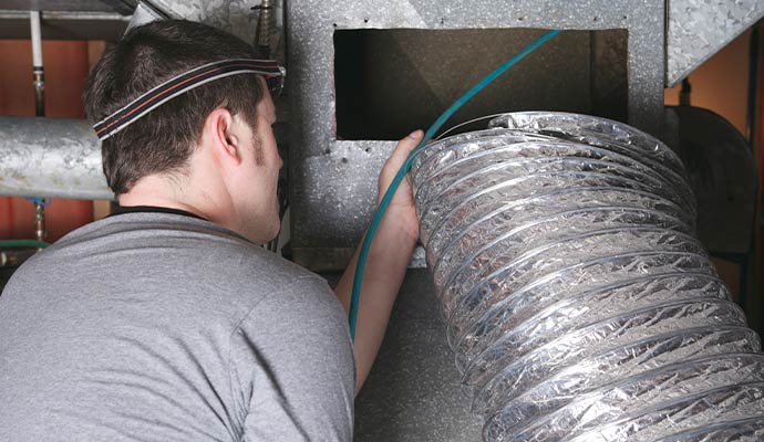 Technician attaching flexible foil duct to metal vent