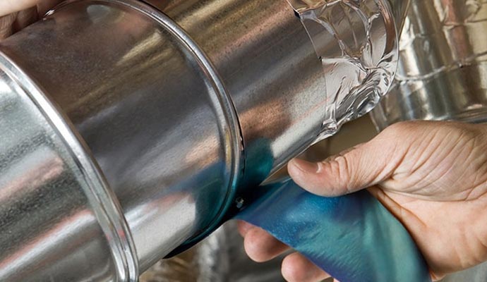 Expert worker using duct tape to seal duct pipe