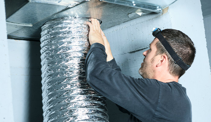 Technician installing flexible aluminum ductwork for ventilation system