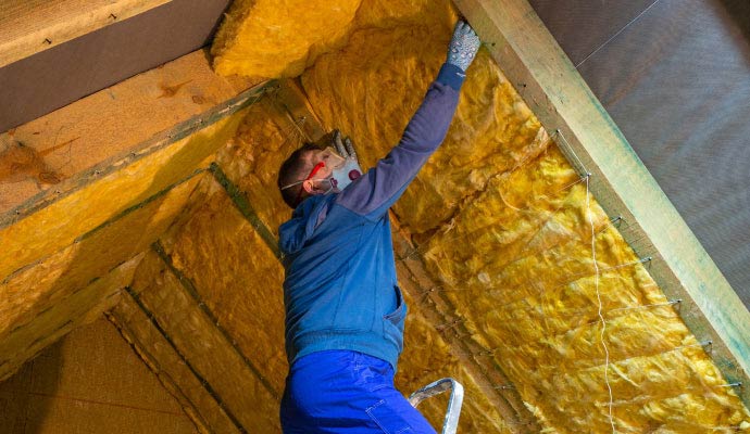 Worker installing fiberglass loft insulation