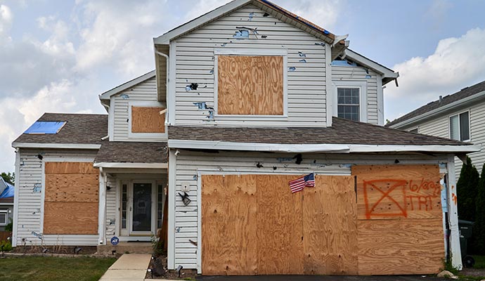 A hail-damaged house is boarded up