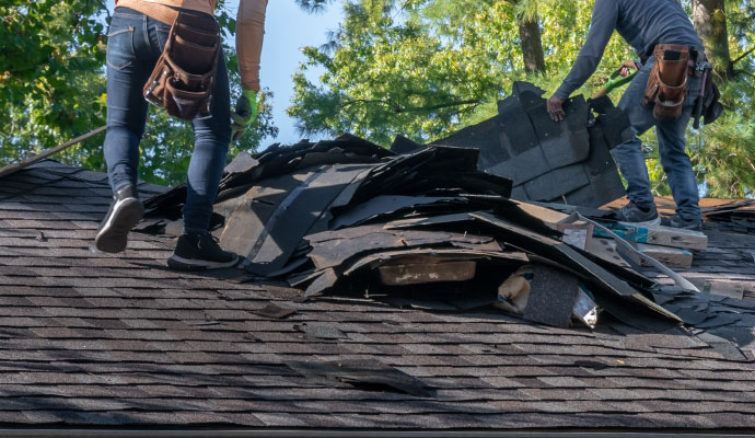 Two experts replacing old damaged roof shingles