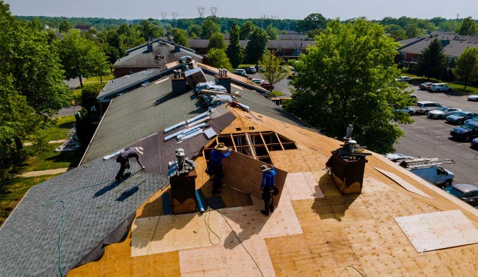 Roofers installing plywood sheathing on roof