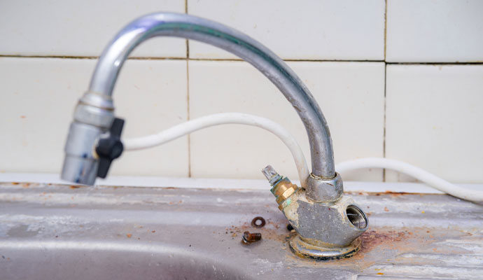 Corroded leaking kitchen faucet with water supply hose