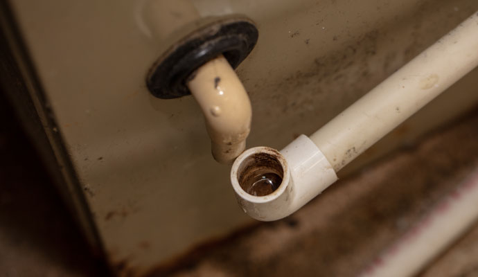 Disconnected PVC condensate drain pipe overflowing water near AC unit