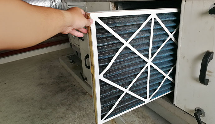 Technician replacing dirty air filter in HVAC unit