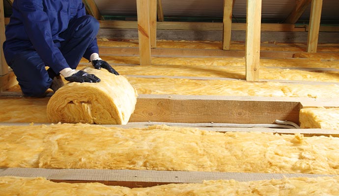 Worker installing attic fiberglass insulation
